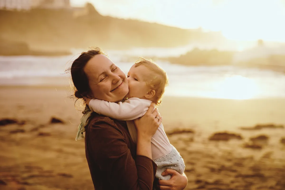 Mama mit Baby am Strand bei Sonnenuntergang